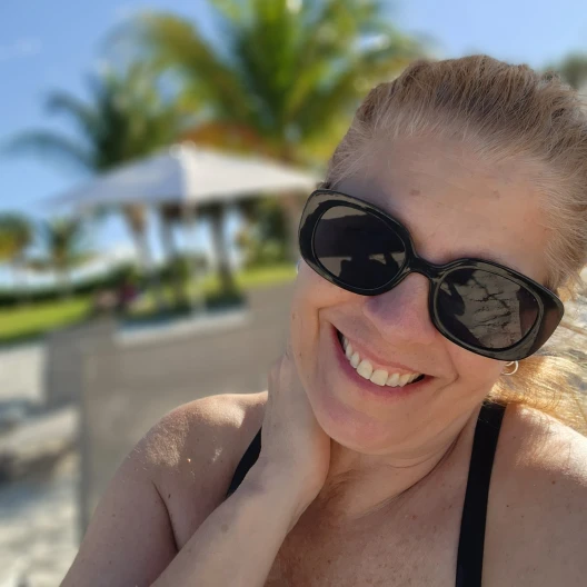 Travel Advisor Sharon Iannone smiling with black glasses on at the beach.
