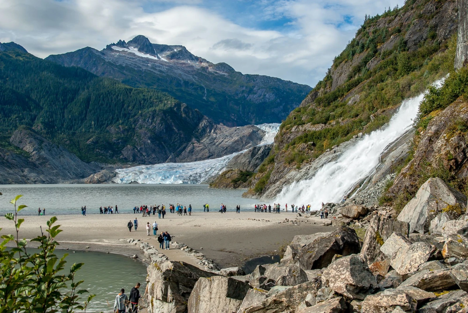 massive glacier with tourists walking at the base