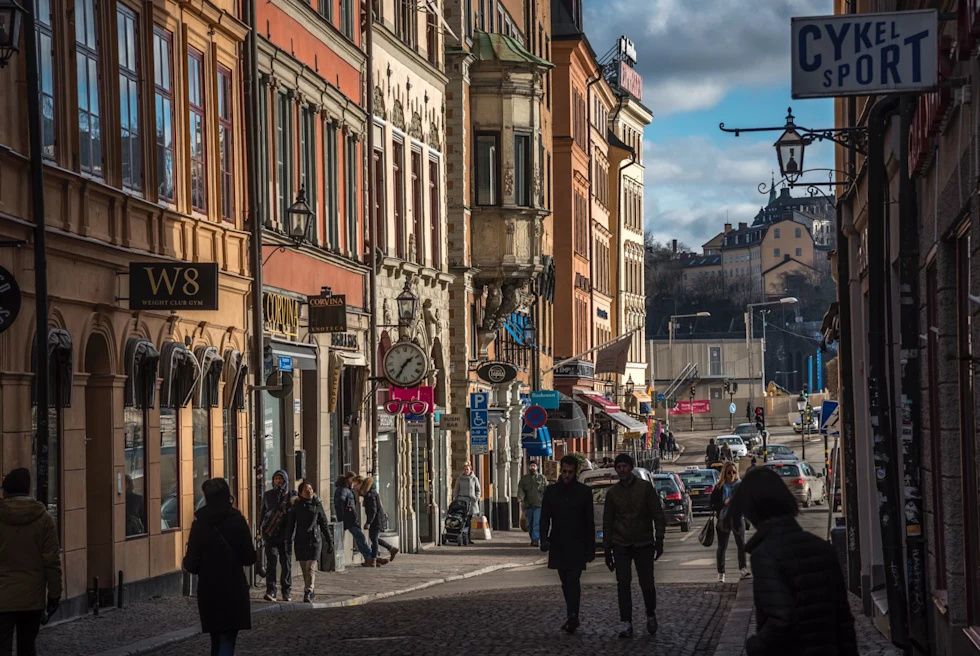 people stroll down small street with colorful buildings