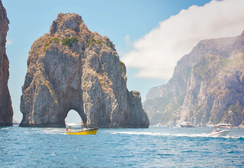 yellow boat in rock formation emerging from the ocean water