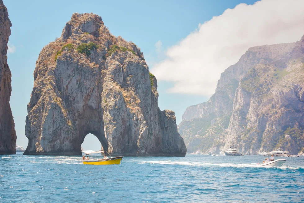 yellow boat in rock formation emerging from the ocean water
