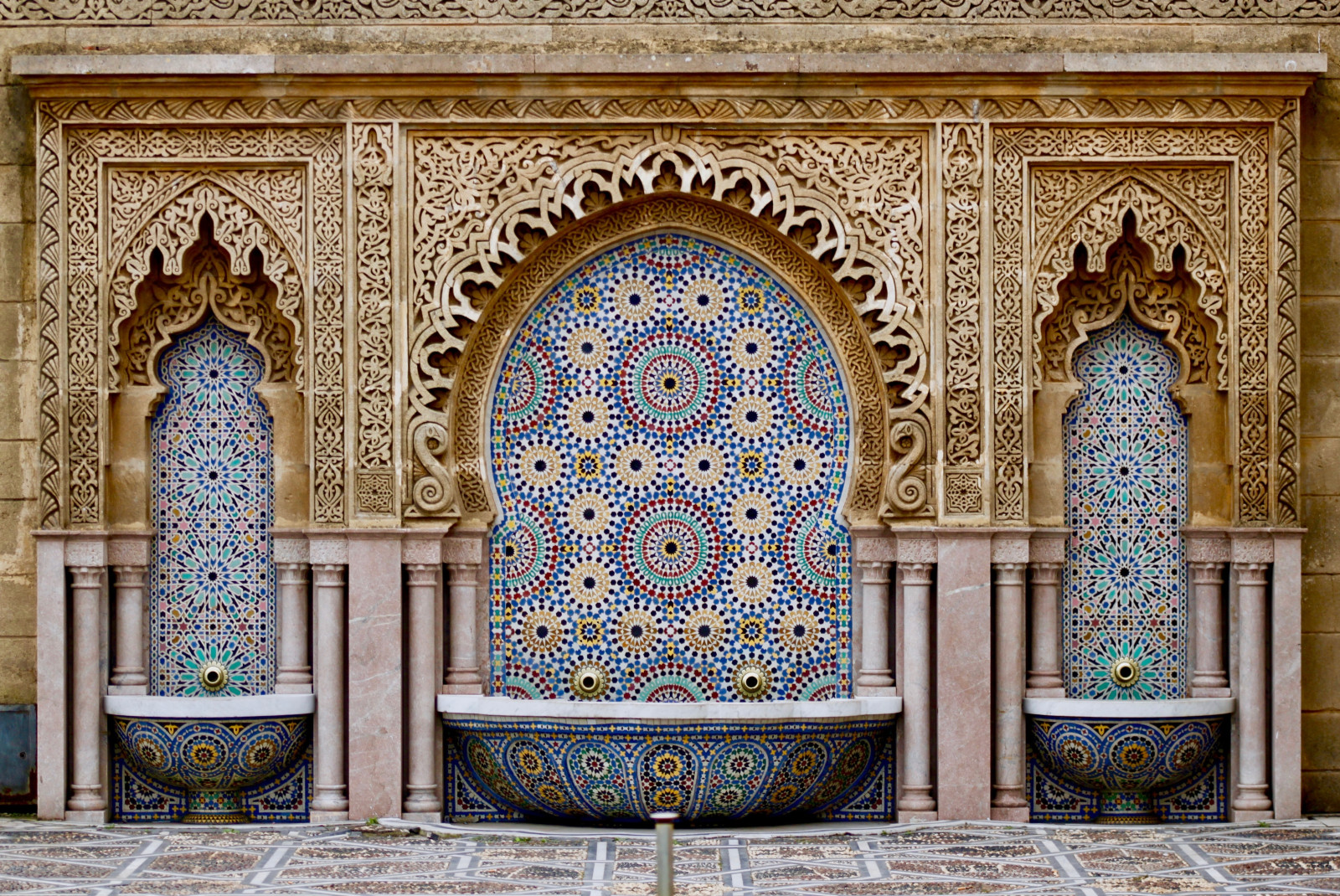 Colorful mosaic of tile on a wall with gold embellishments.