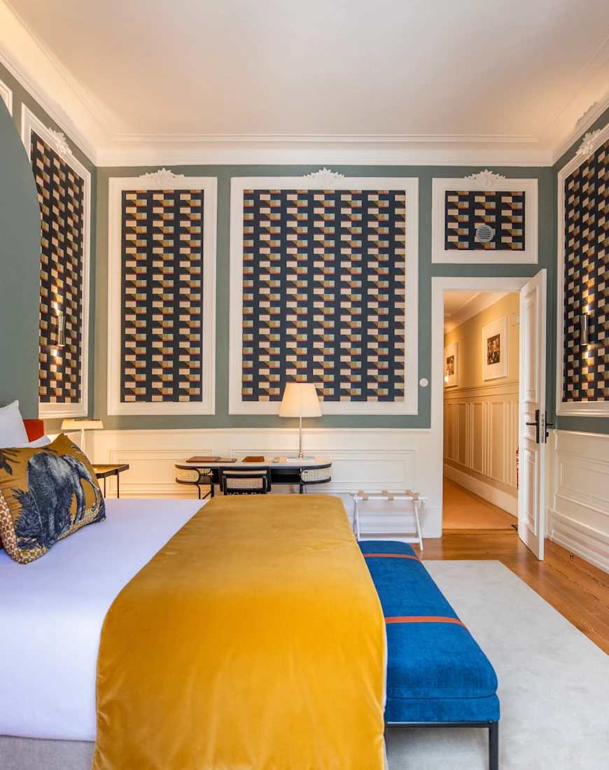 a bright hotel room with turquoise walls and a bed with a yellow blanket