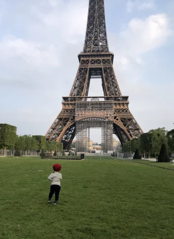 A kid running in front of Eiffel Tower.
