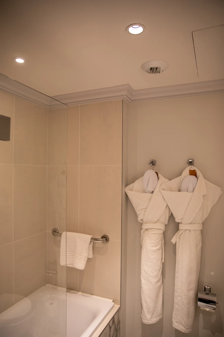 A hotel bathroom with two robes hanging up