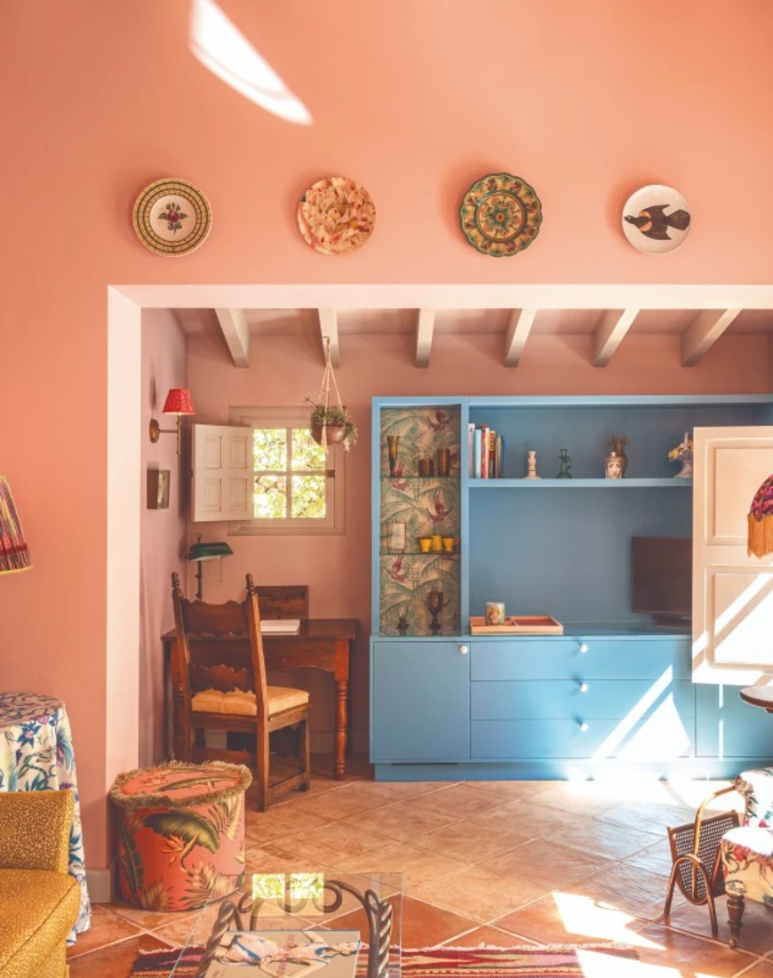 a seating area with pink walls and furniture covered in floral prints