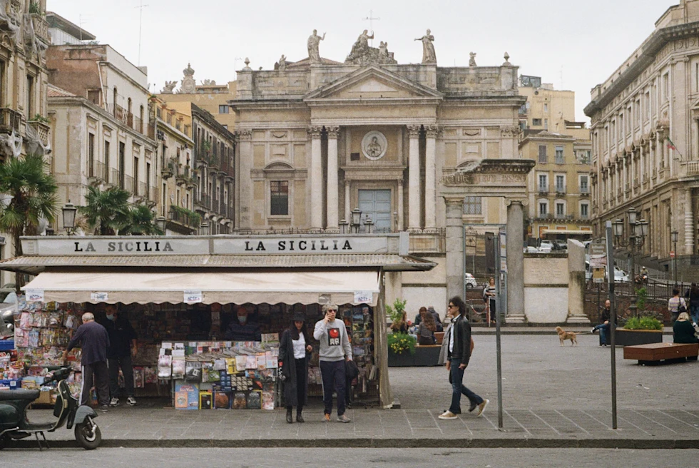 people on the side of the street with large building in the background