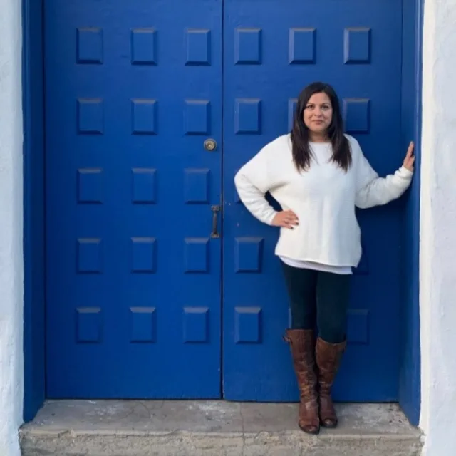 Travel advisor posing in front of a blue gate