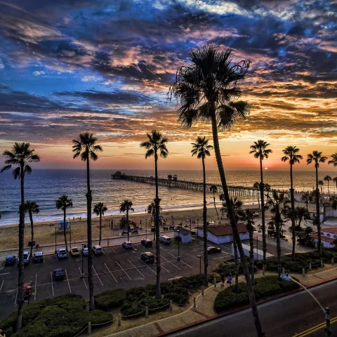 A beautiful view of Oceanside beach with palm trees and a jaw dropping sunset. 