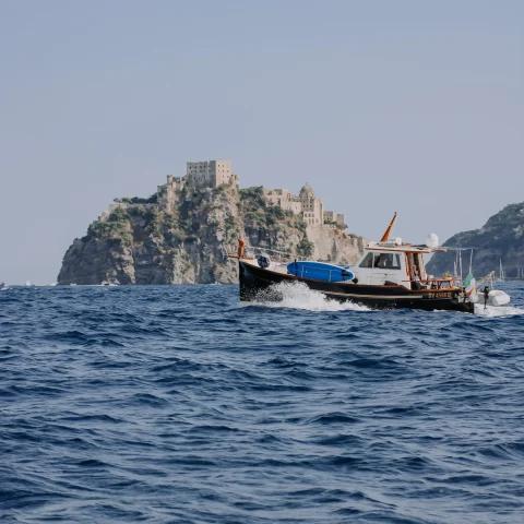 Boat on the water in front of Castello Aragonese in Ischia, Italy