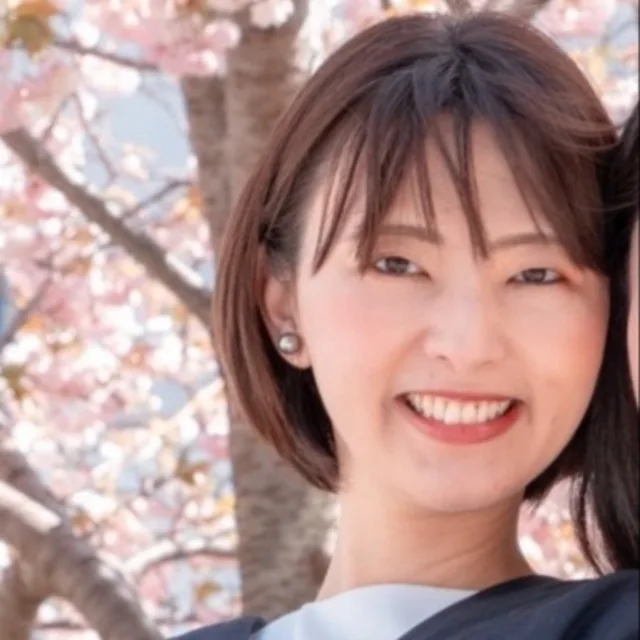 Travel Advisor Manami Yamamoto's head shot with cherry blossom trees in the background. 