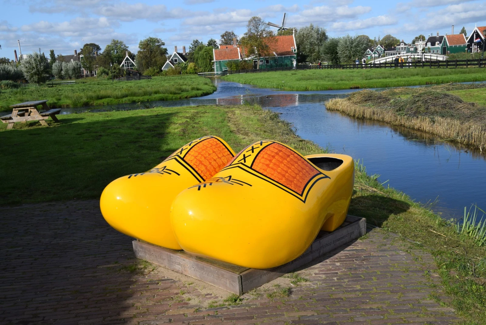 yellow clogs sit on the rock in front of a charming town on a small river