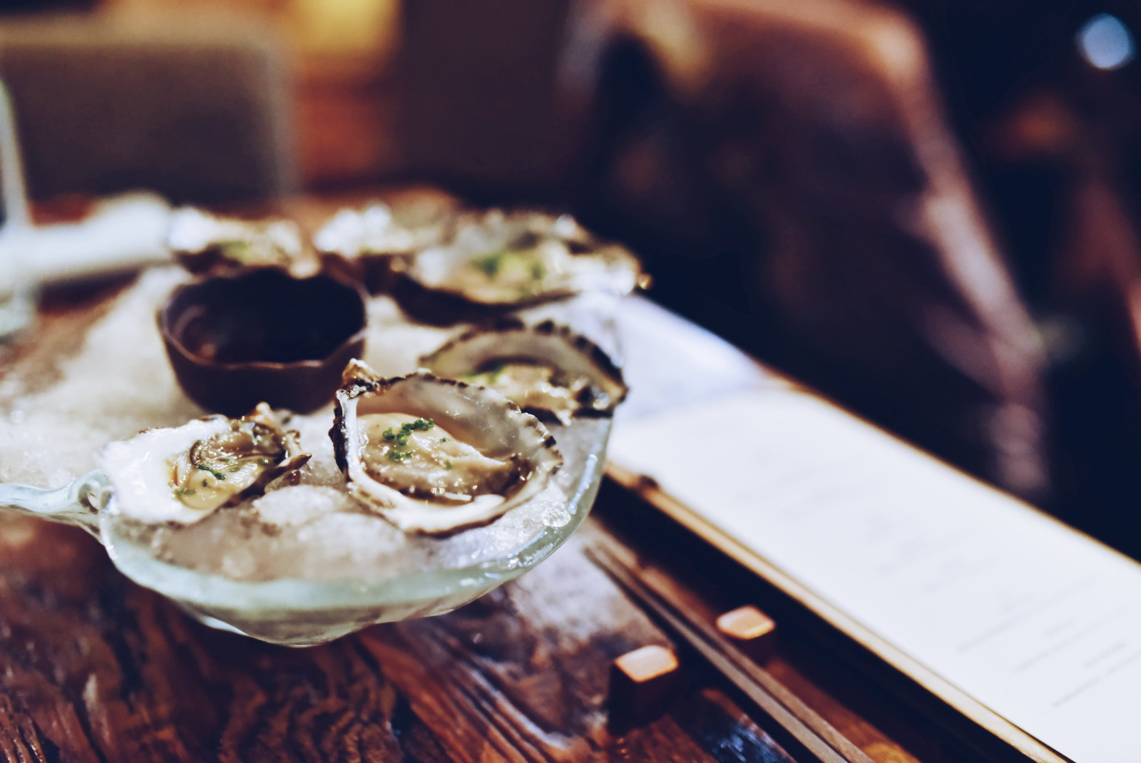 Oysters in a glass dish on a wooden table