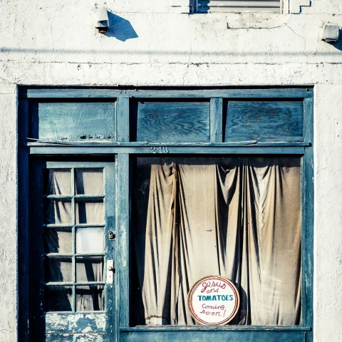 A older shop with blue window and curtains.