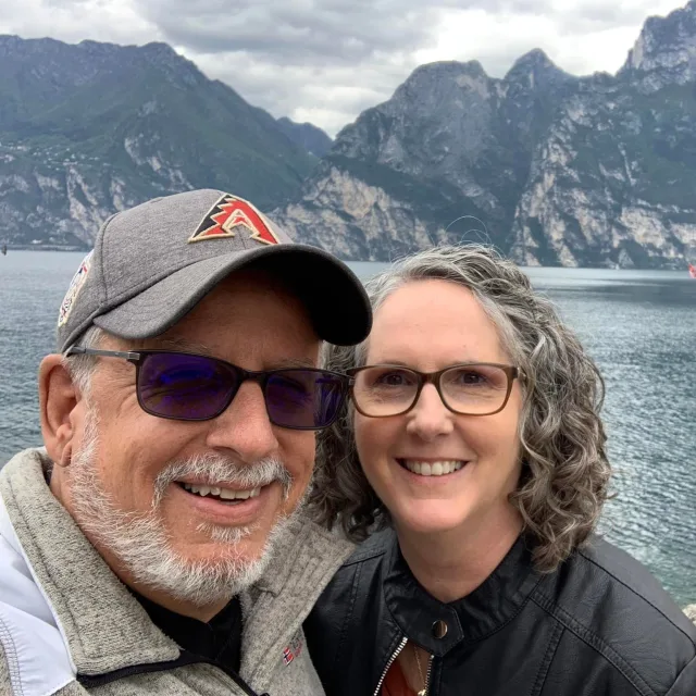 Travel advisor Allen Bartimioli posing with her husband in front of a lake.