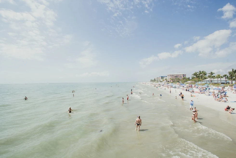 white sand beach with bathers in the water and on the shore