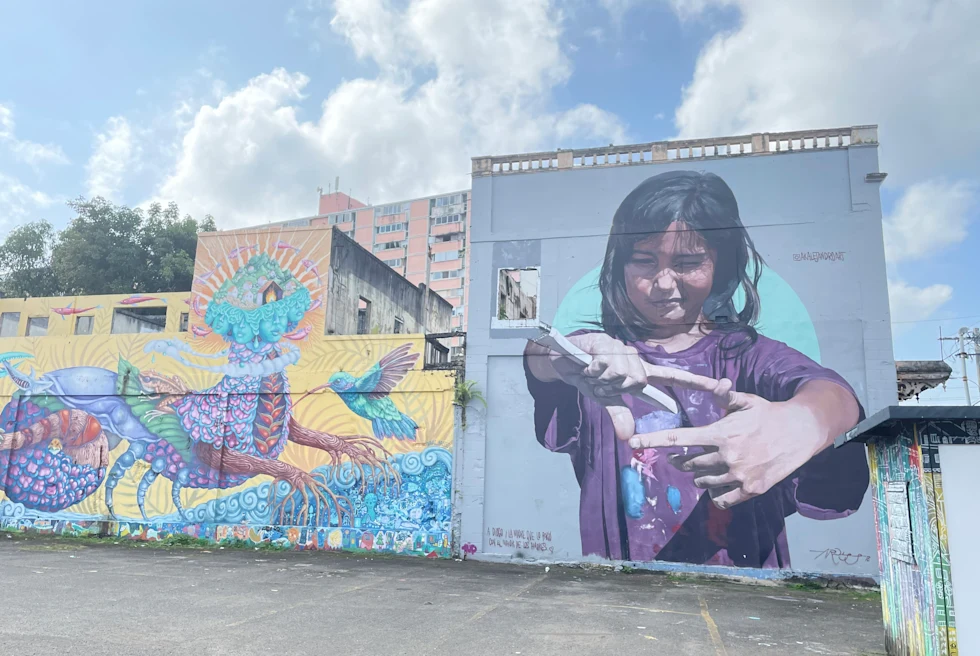 Colorful art on side of building with clouds in the sky during daytime