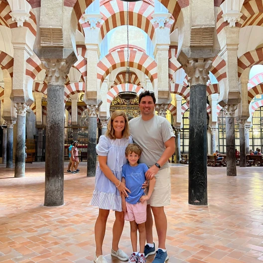 Travel Advisor Gray Grandy with her husband and son and brown/white arches behind.
