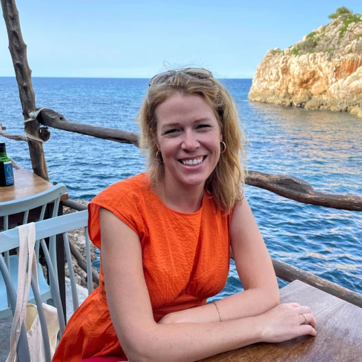 Travel Advisor Jessica Rodgers wears an orange dress at a restaurant on the water