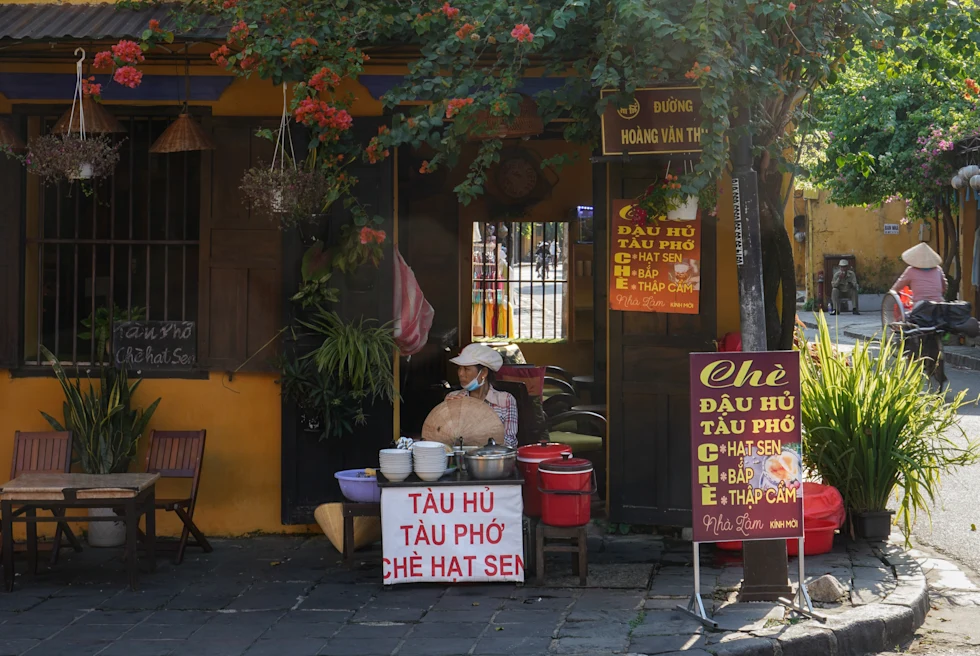 Woman sitting outside an orange building under a tree