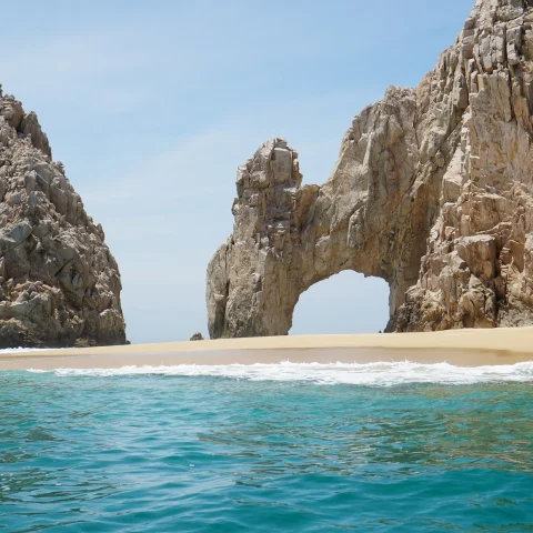 beachside cliffs with blue water and tan san in los cabos mexico