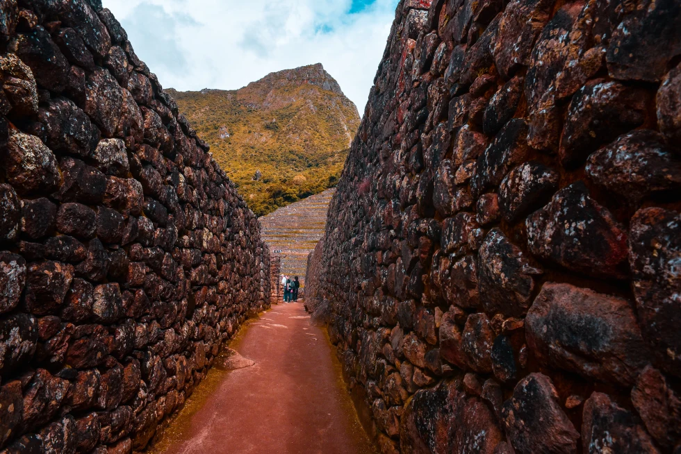Red and brown stone walls with large mountains in the background at Machu Picchu in Peru.