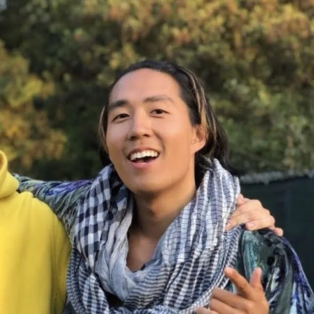 Travel Advisor Jeff Tang wears a black and white patterned scarf with an open smile