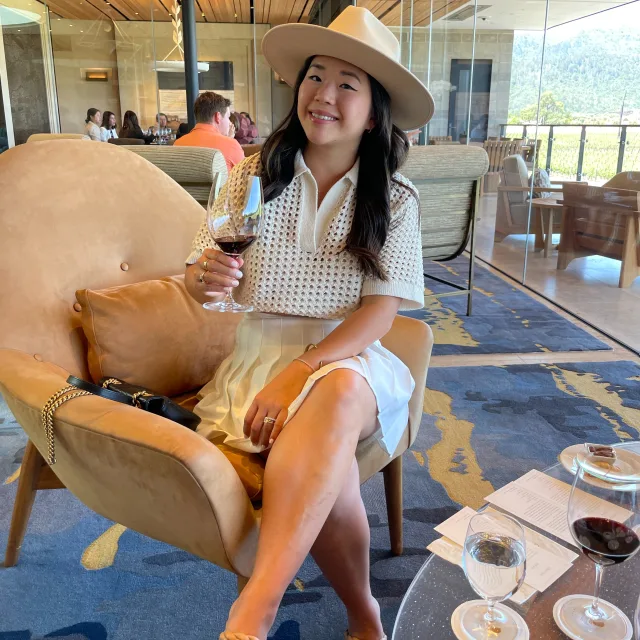 Travel Advisor Nora Clark holding a glass of wine sitting in a chair.