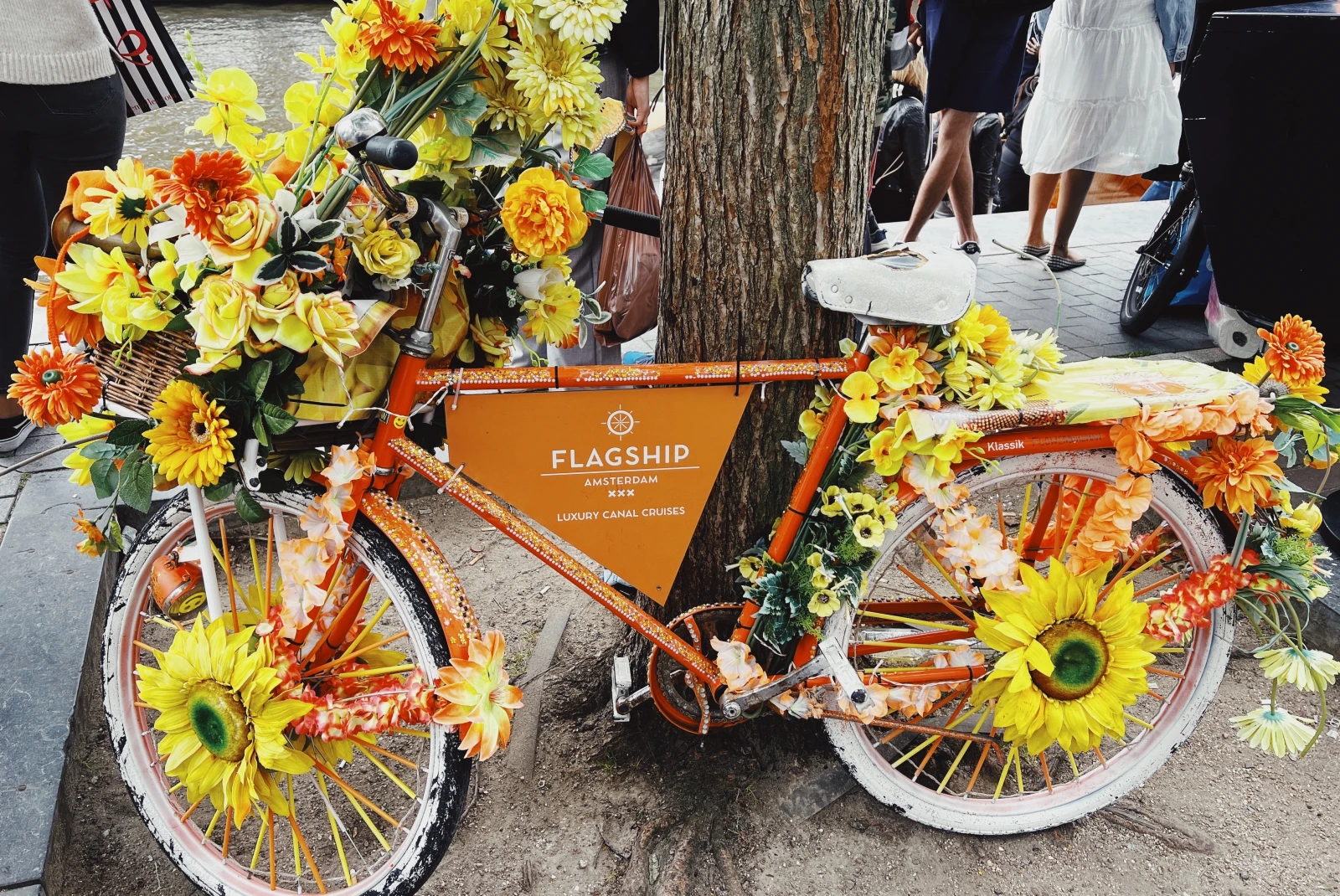 An orange bicycle landmark decorated with yellow and orange flowers. 