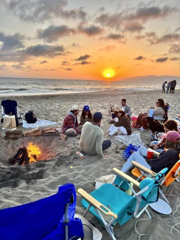 People sitting on beach at sunset.
