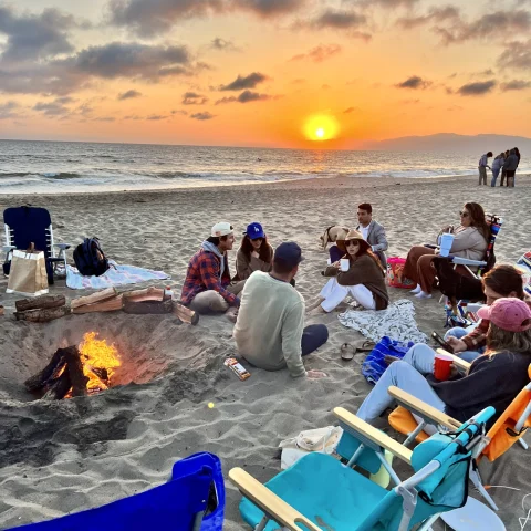 People sitting on beach at sunset.