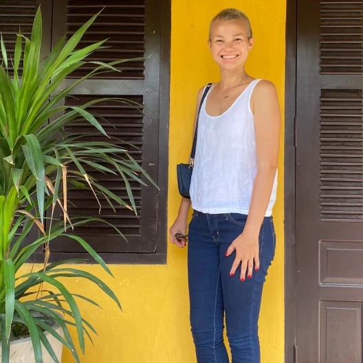 Travel advisor Sequoia Armstrong posing in front of a bright yellow house.