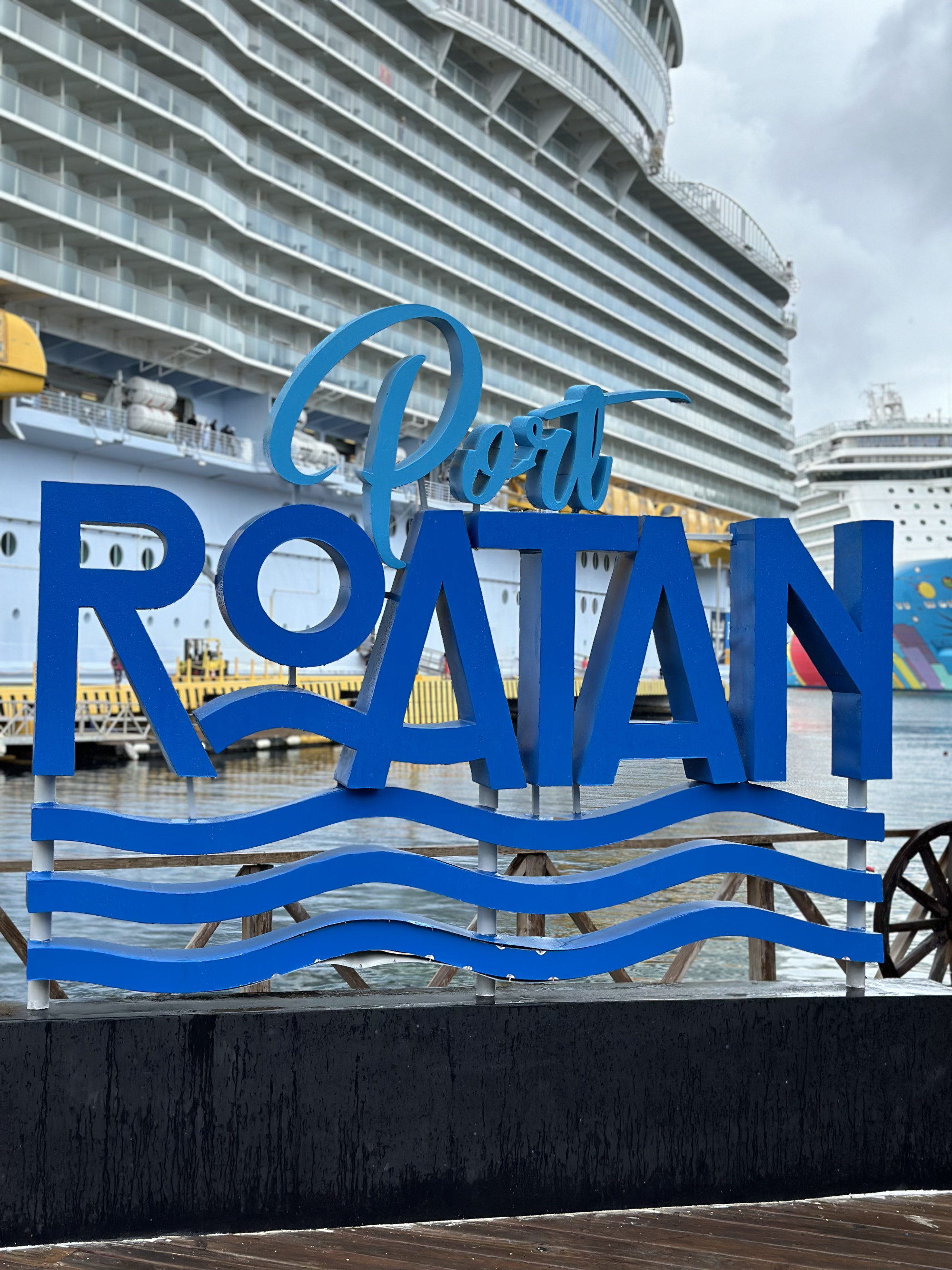 A sign reading "Port Roatan" in front of a cruise ship