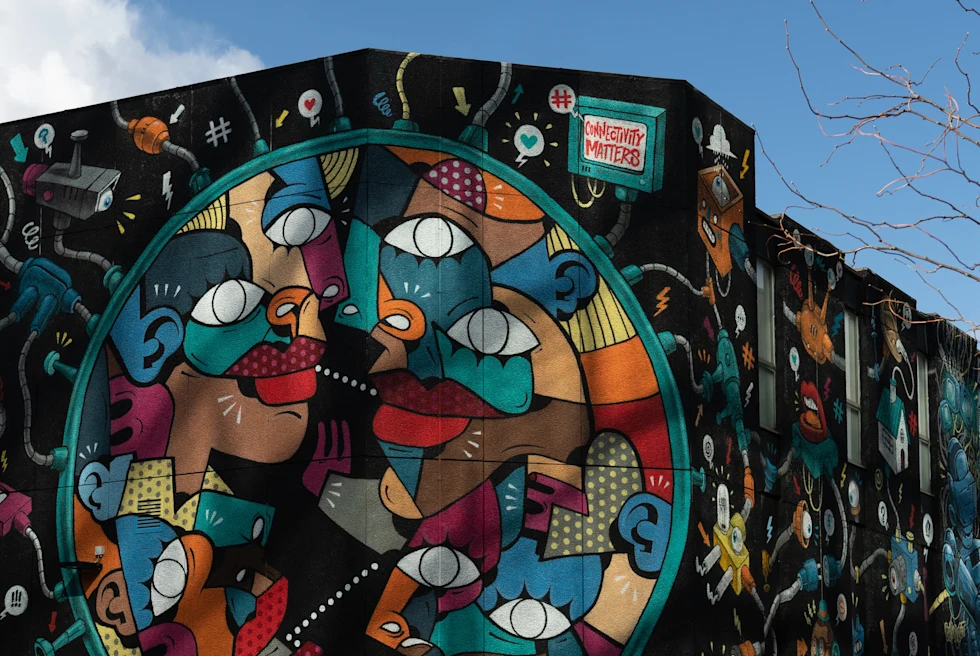 Blue yellow red brown faces and street art on a black brick wall in Shoreditch in London, England.