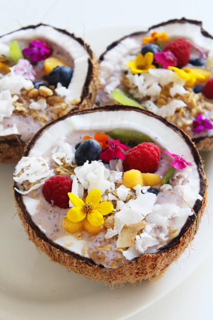Acai topped with fruit and flowers served in a coconut