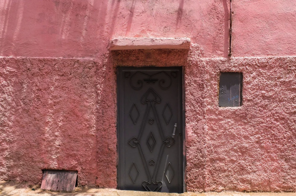 pink wall with small door at the entrance of a medina