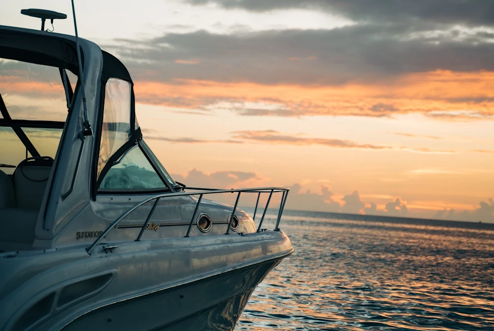 a speed boat floats on the open ocean at sunset
