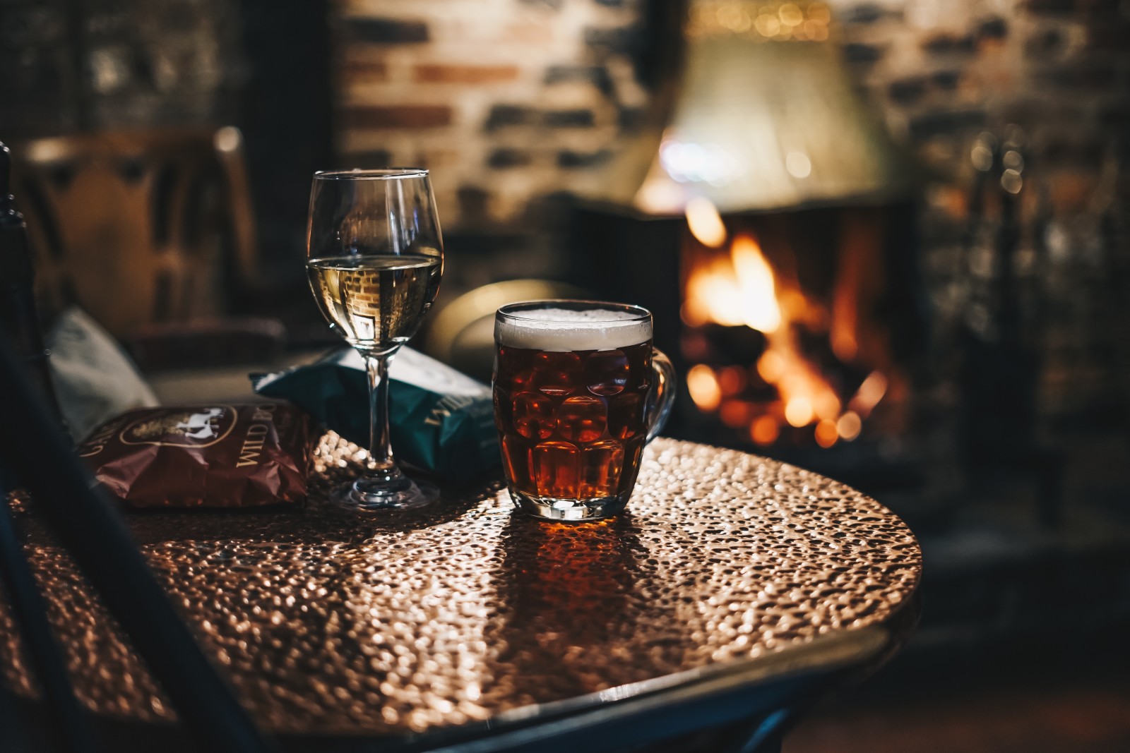 glass of beer and wine on table with fire in the background