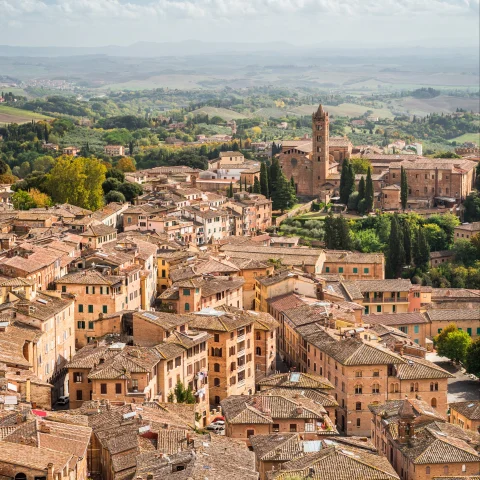 Aerial views of a village surrounded by green fields in Tuscany. 