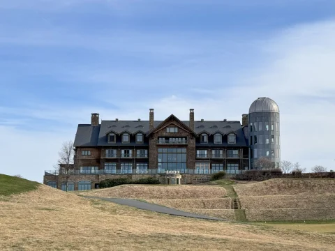 A picture of Primland Resort, a large brick building, set on a hill with grassy grounds.