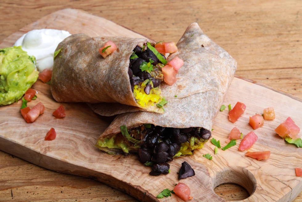 Breakfast burrito on a wooden board.