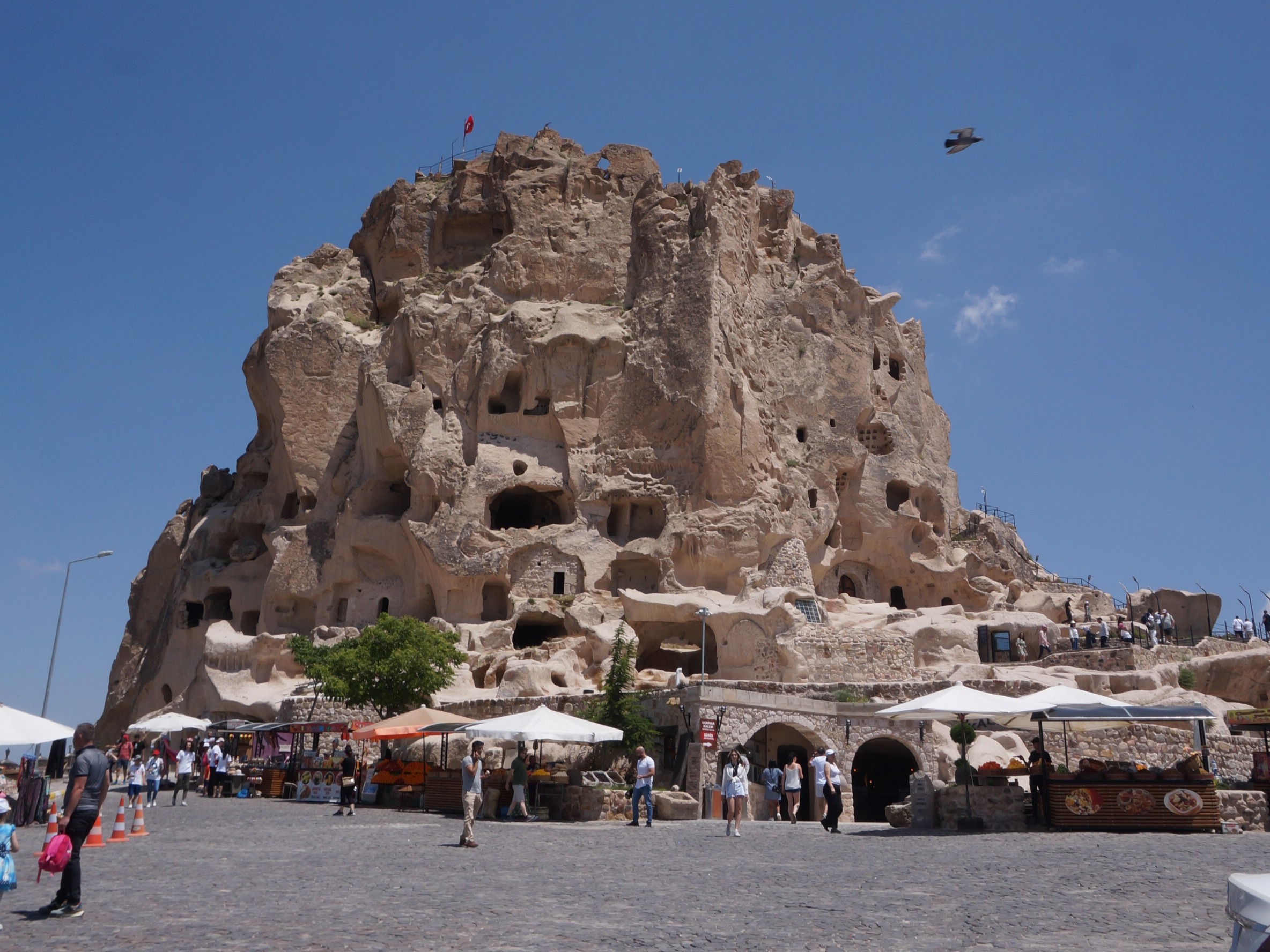 A large structure build out in a brown hill with market stalls around it
