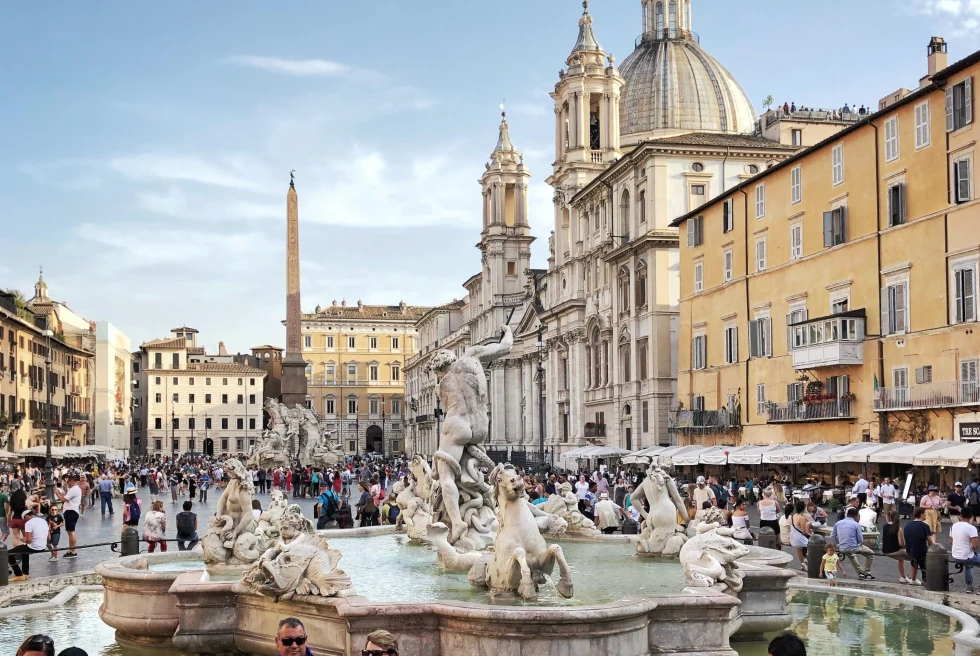 Fountains and statues surrounded by buildings and people. 