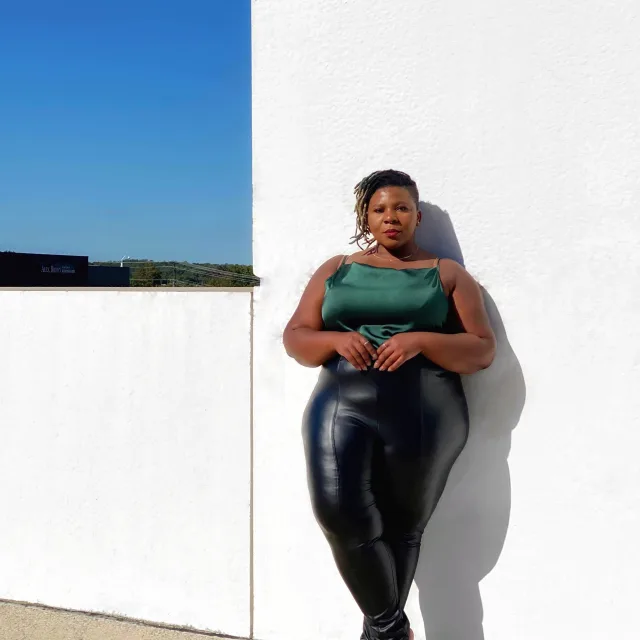 Woman standing in front of white wall smiling