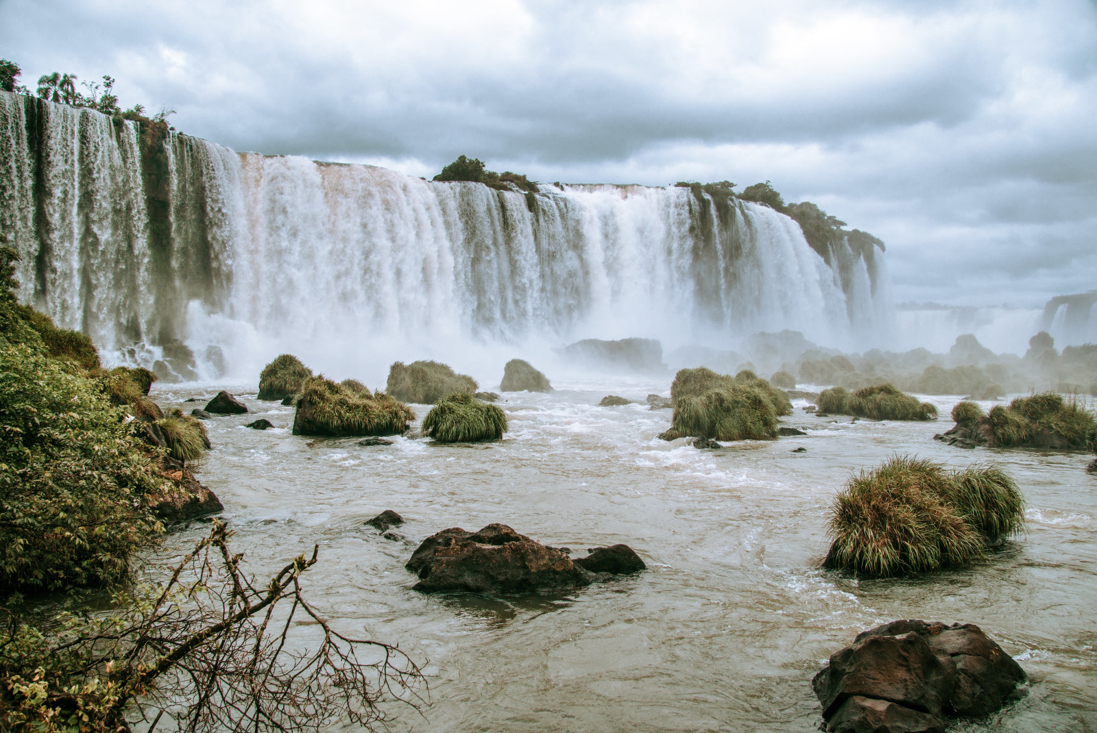 Foz de Iguaçu waterfalls with white rushing water crashing into a pool with rocks in Brazil.