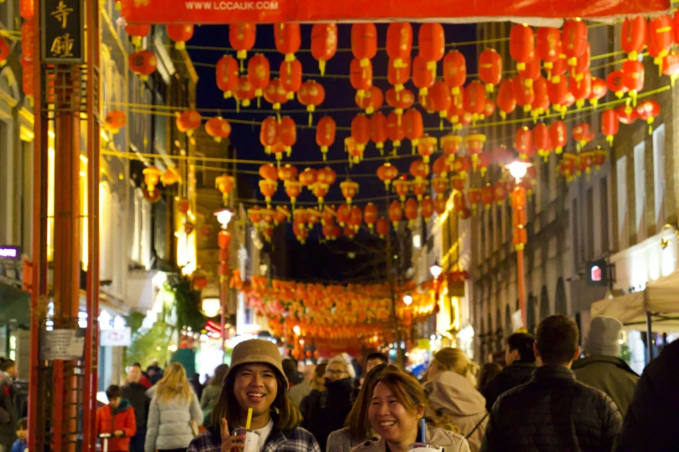 A group of people walking on the streets with orange lanterns. 