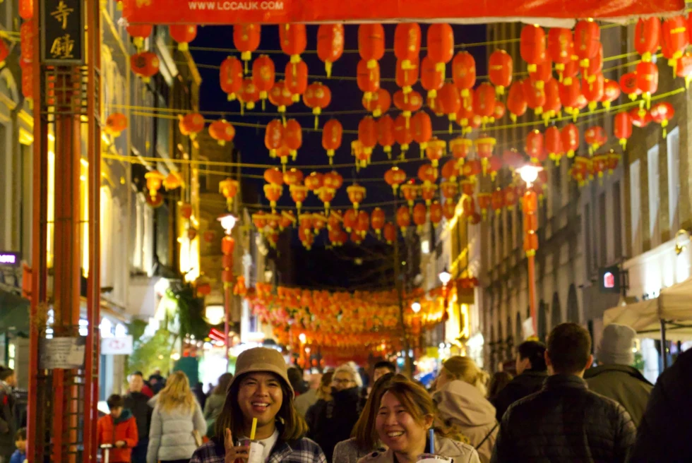 A group of people walking on the streets with orange lanterns. 