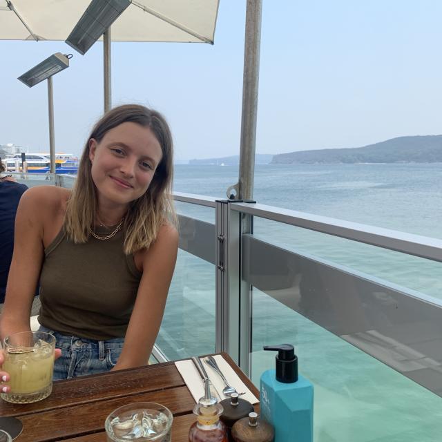 Caneel Lange-Blom Travel Agent sitting with drink at oceanfront restaurant