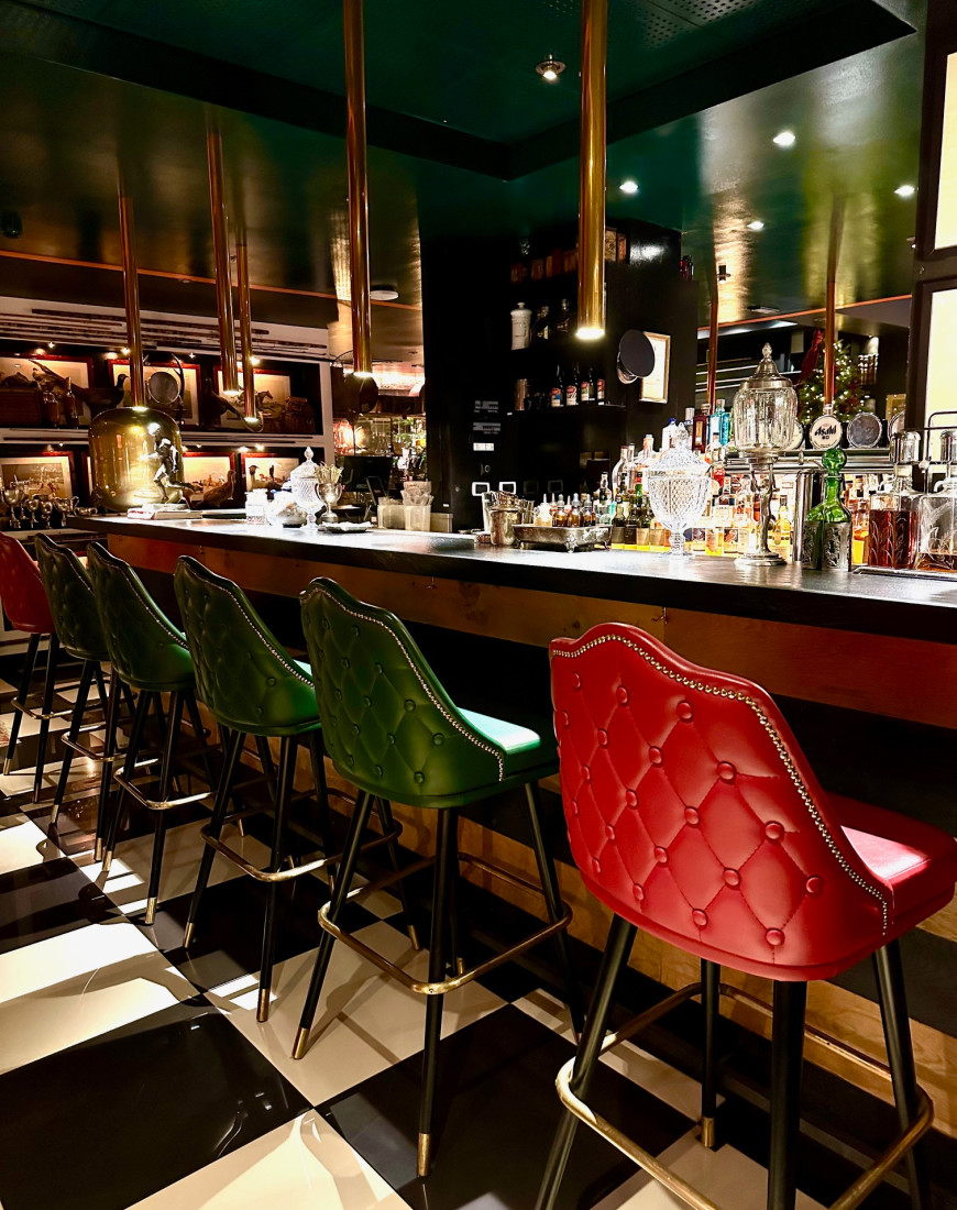 An indoor bar with red and green chairs