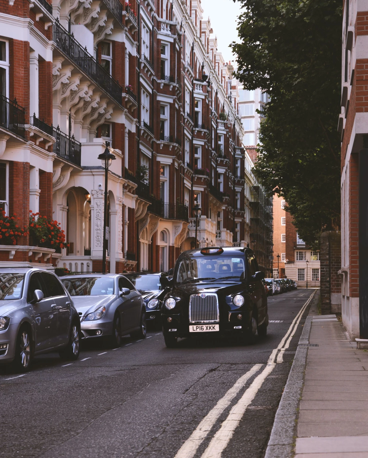 black cab drives down street with brick buildings